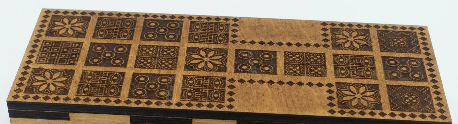 Top-down view of the Ancient Origins Royal Game of Ur board. The wide block is on the left, five flower rosettes are engraved on the squares, and the panels beside the bridge are plain wood.
