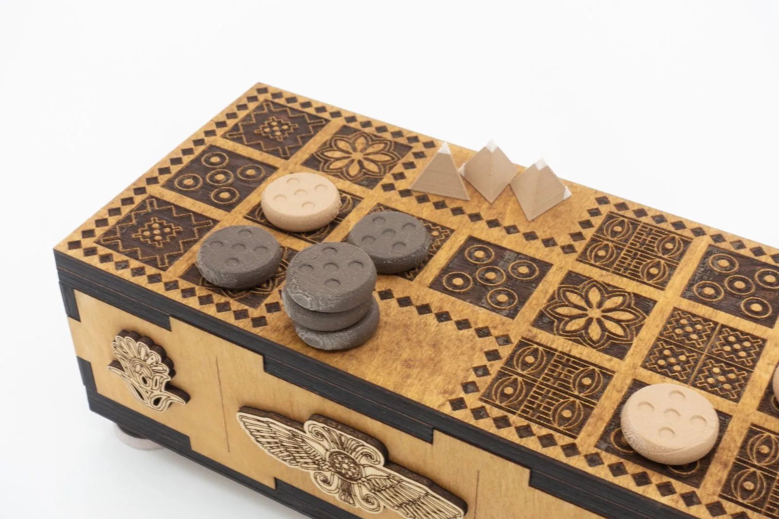 Round light and dark playing pieces, each marked with five dots, and tan tetrahedral dice on the Ancient Origins Royal Game of Ur board.